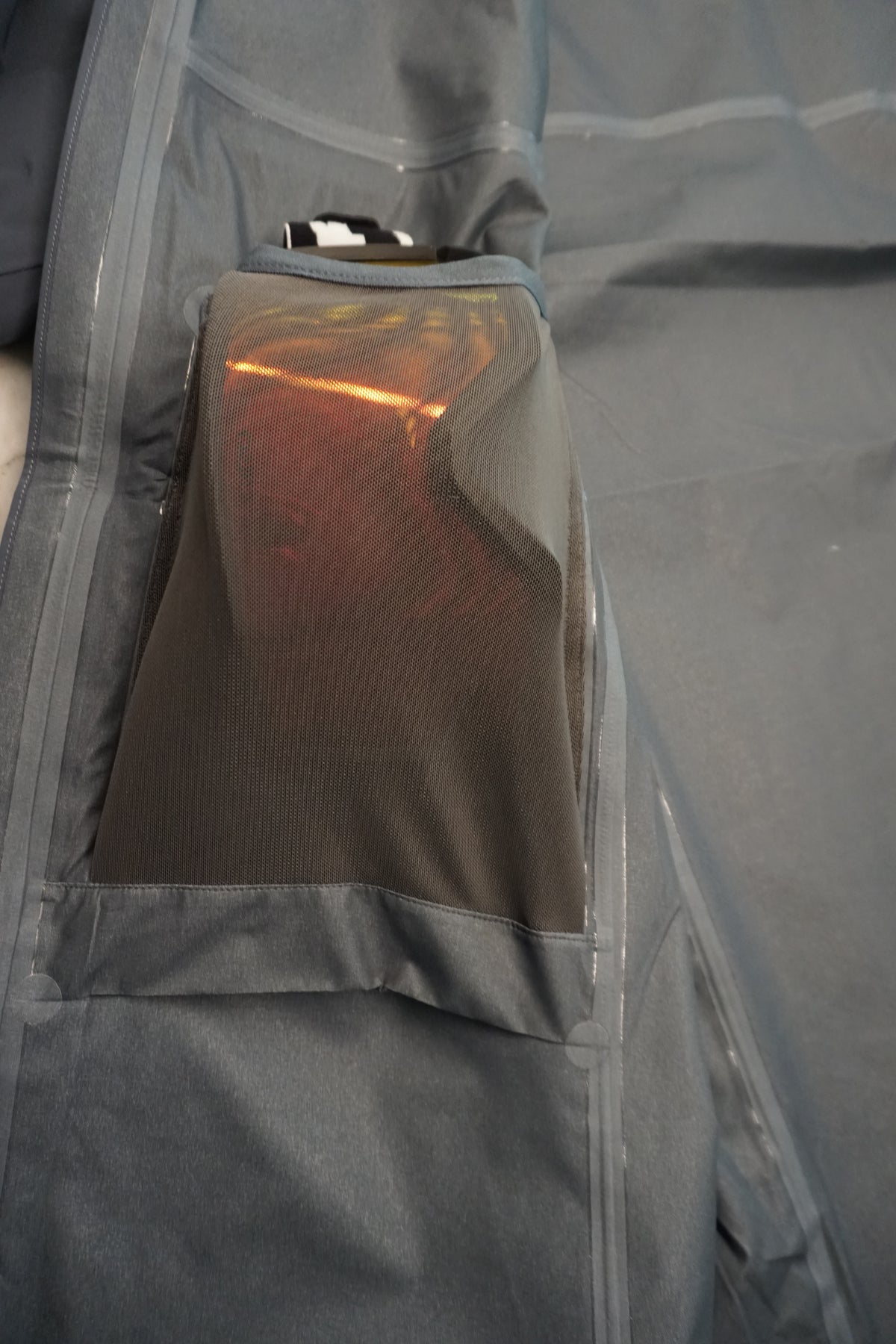 Grey elastic drop pocket inside technical shell with snow goggles inside of it.