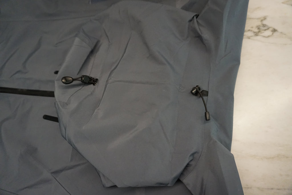 The back of the hood of a grey snow shell with 4 point adjustable toggles.