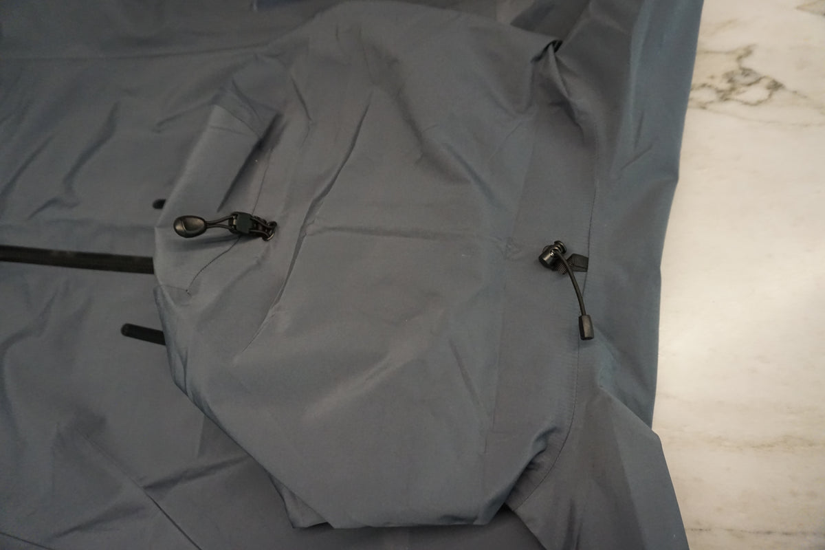 The back of the hood of a grey snow shell with 4 point adjustable toggles.