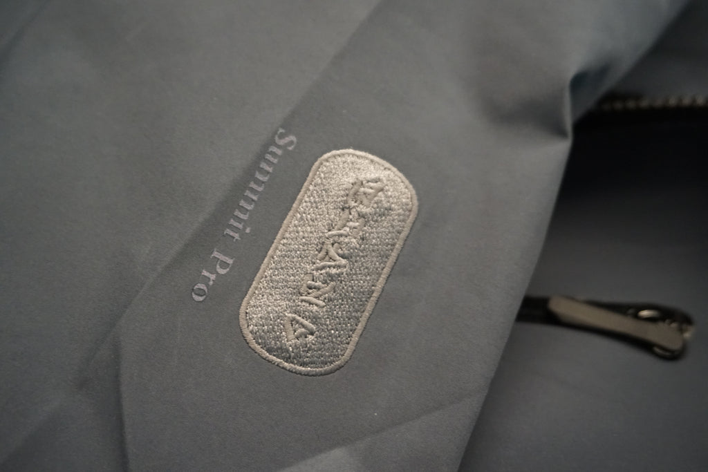 Embroidered identity patch on the arm of the technical shell.