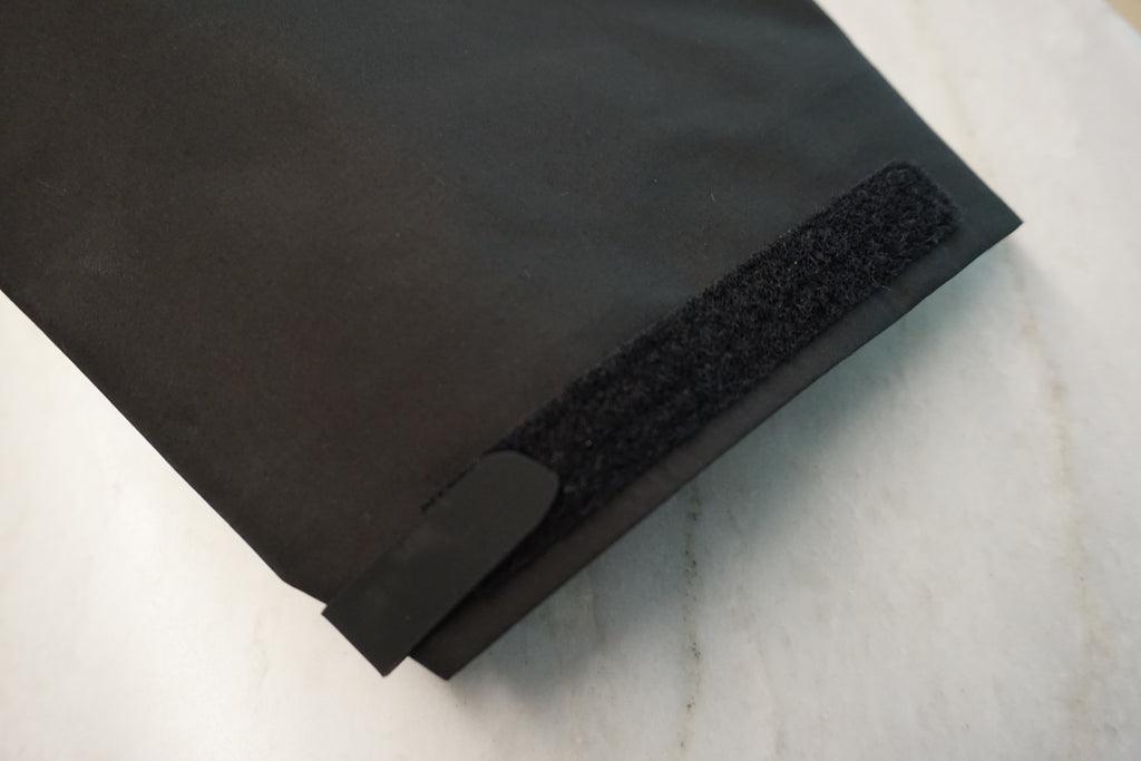 A close-up of the velcro cuff closure on a black jacket.