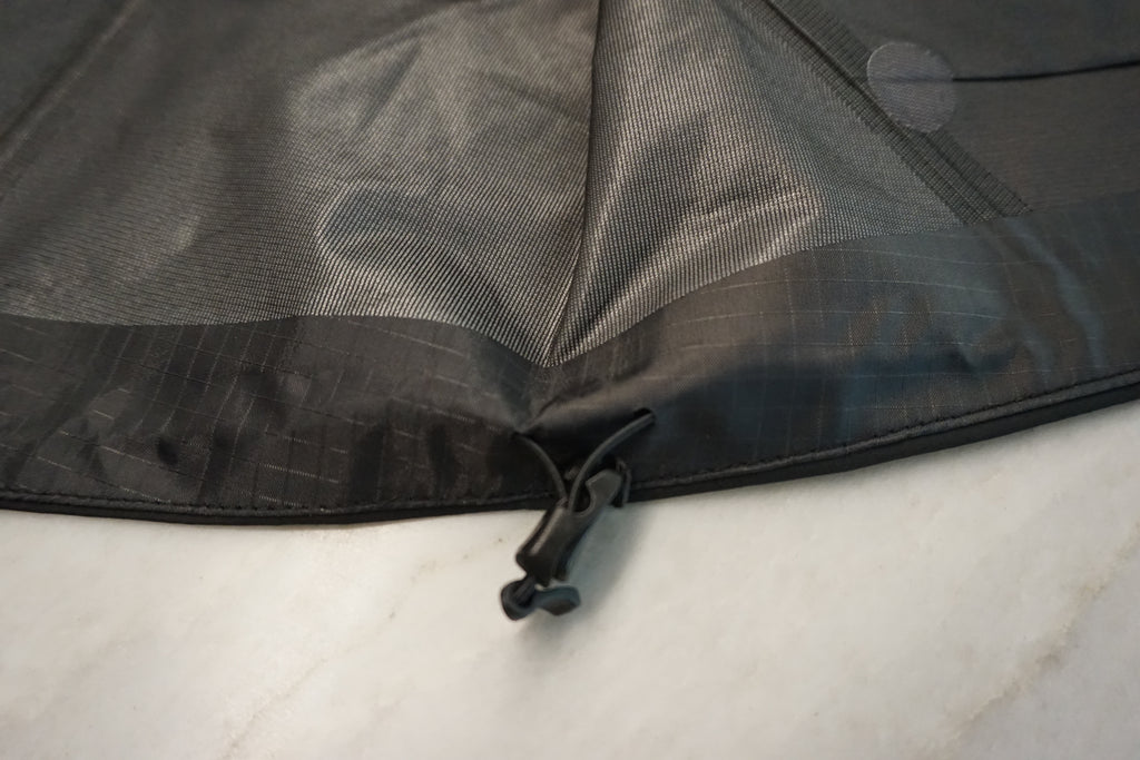 Close-up of the hem sinch of a black waterproof shell.