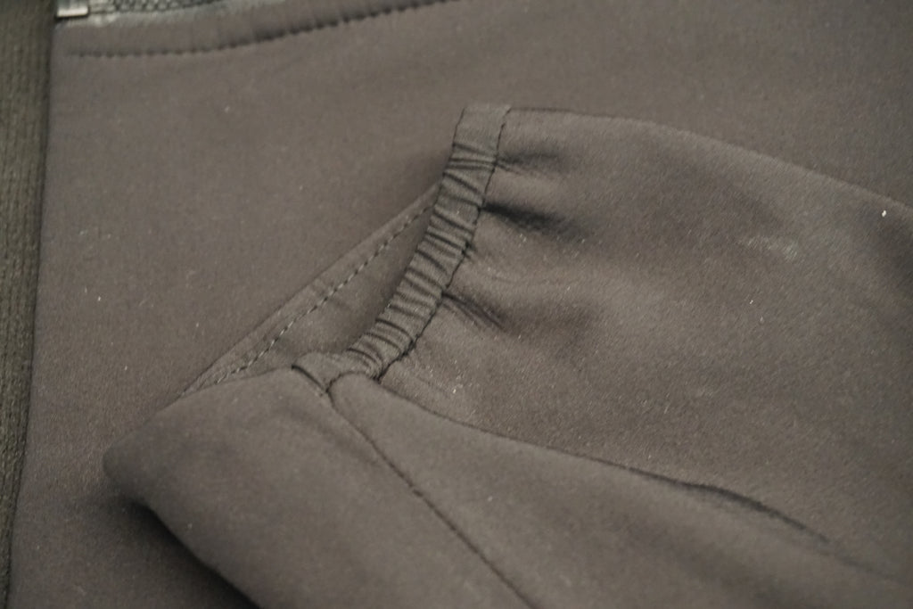 Close-up of a black fabric garment, showing the cuff of the jacket's elastic end.