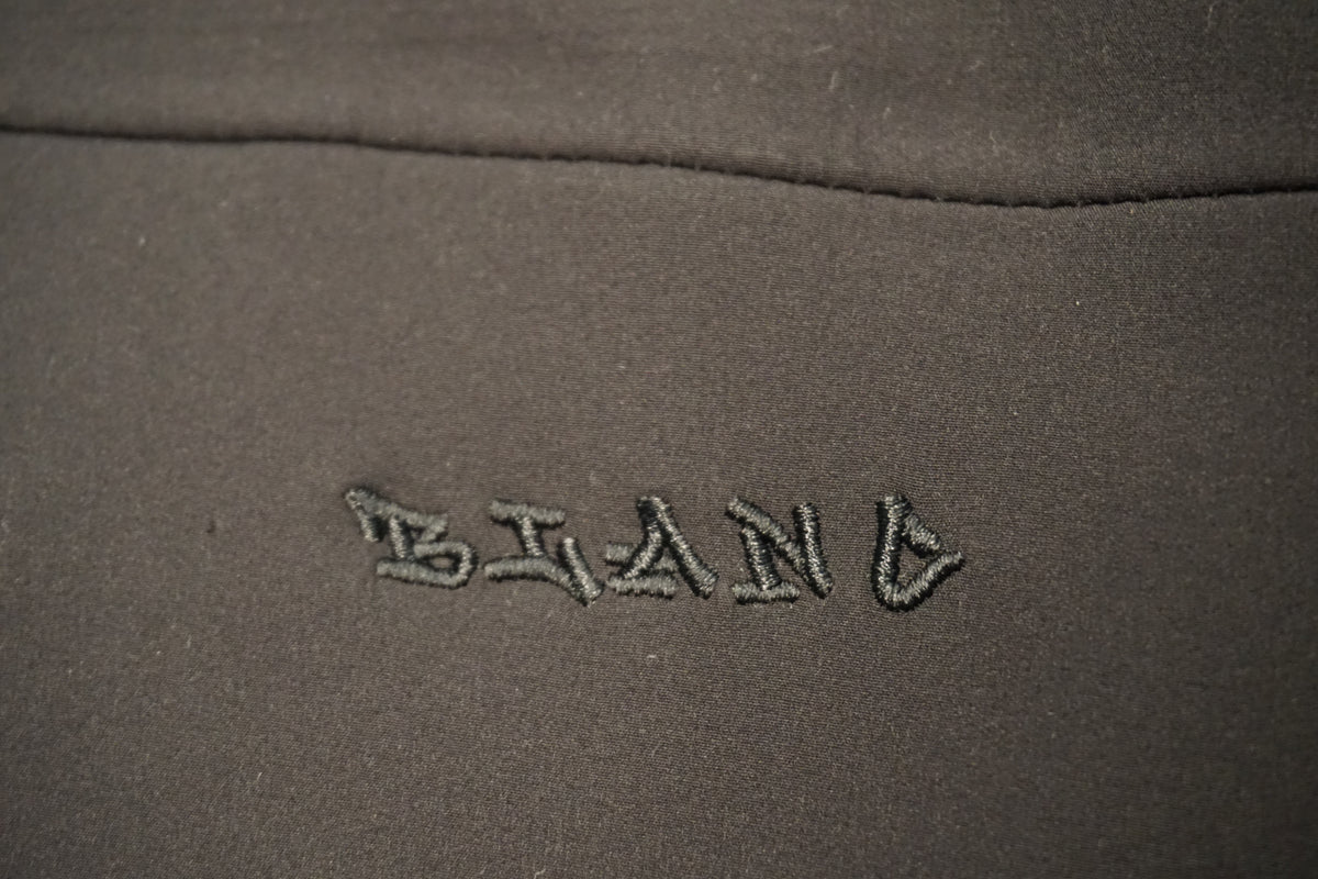 Close-up of a black fabric surface with the word 'BLANC' embroidered in matching black thread.