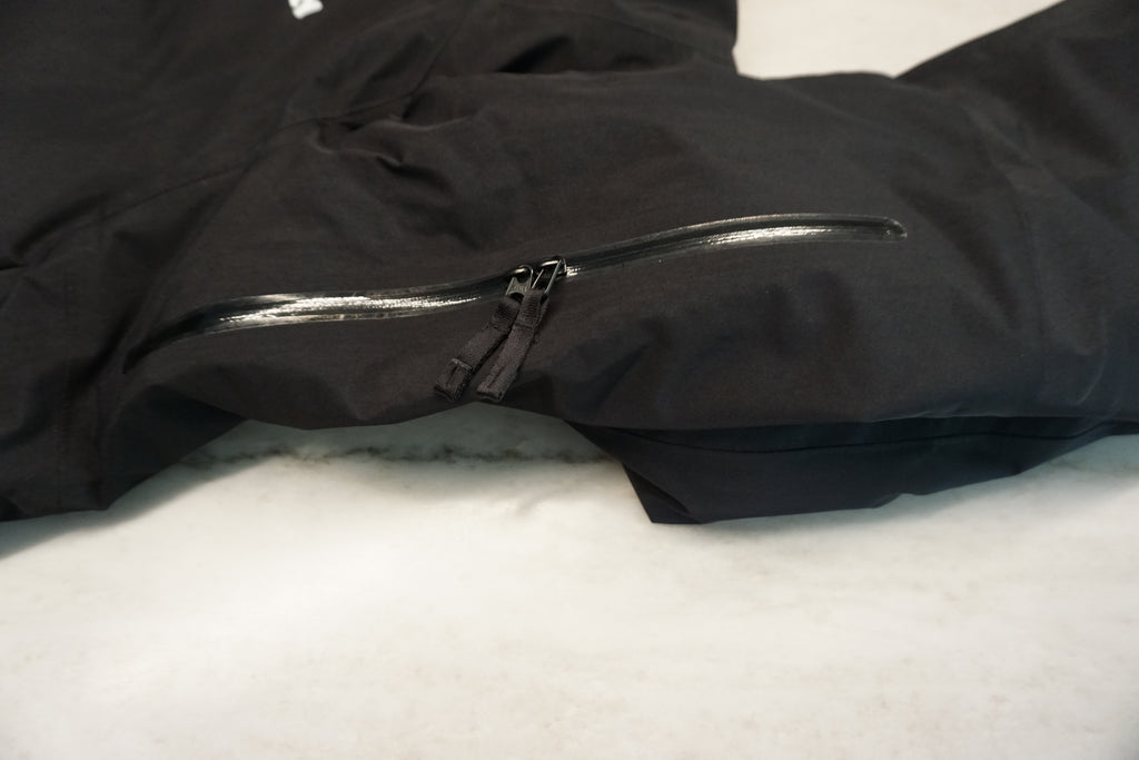Close up of dual zipper underarm zippers on a black snow jacket.